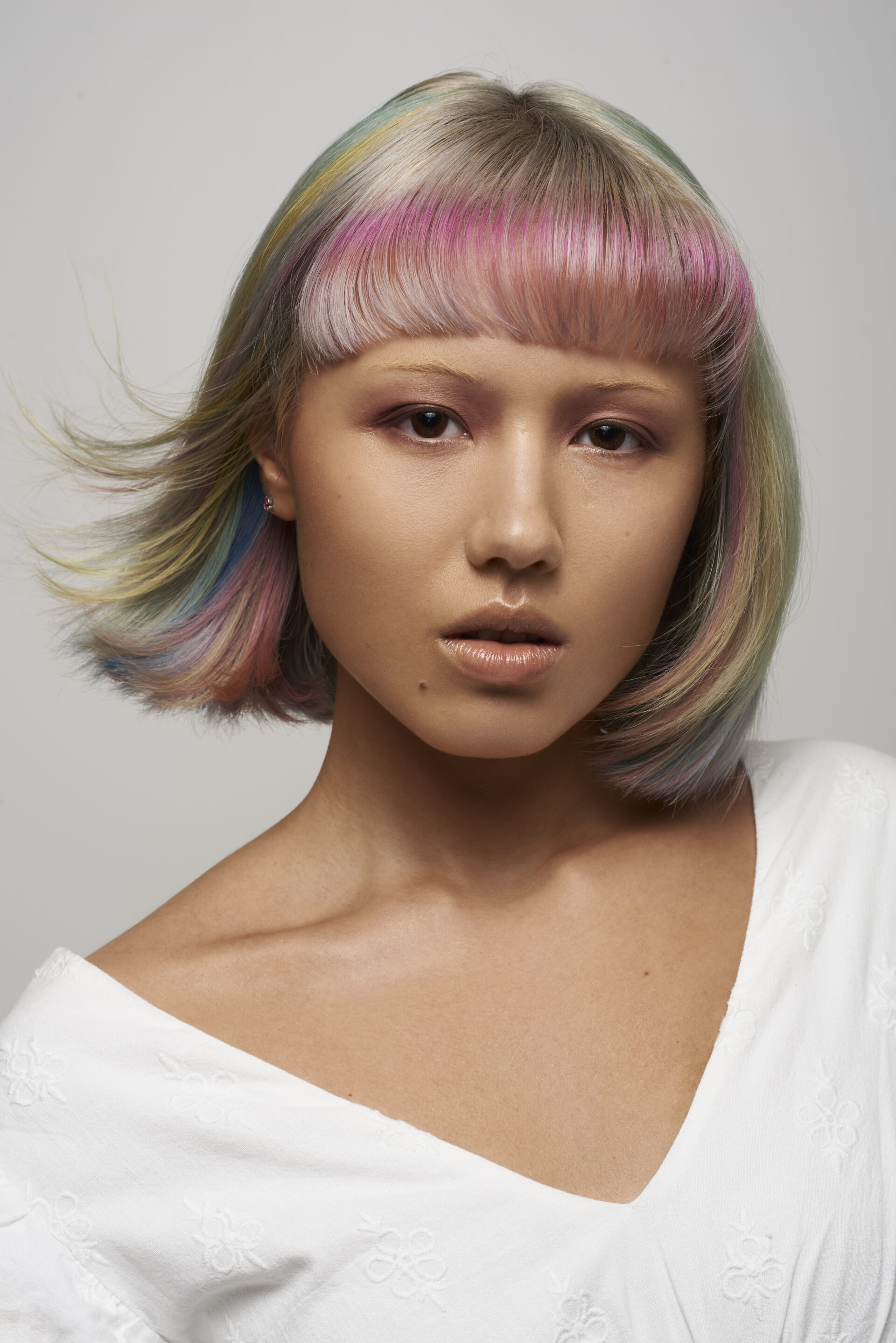 Model on a grey background with Pink, Blue, Yellow coloured hair.