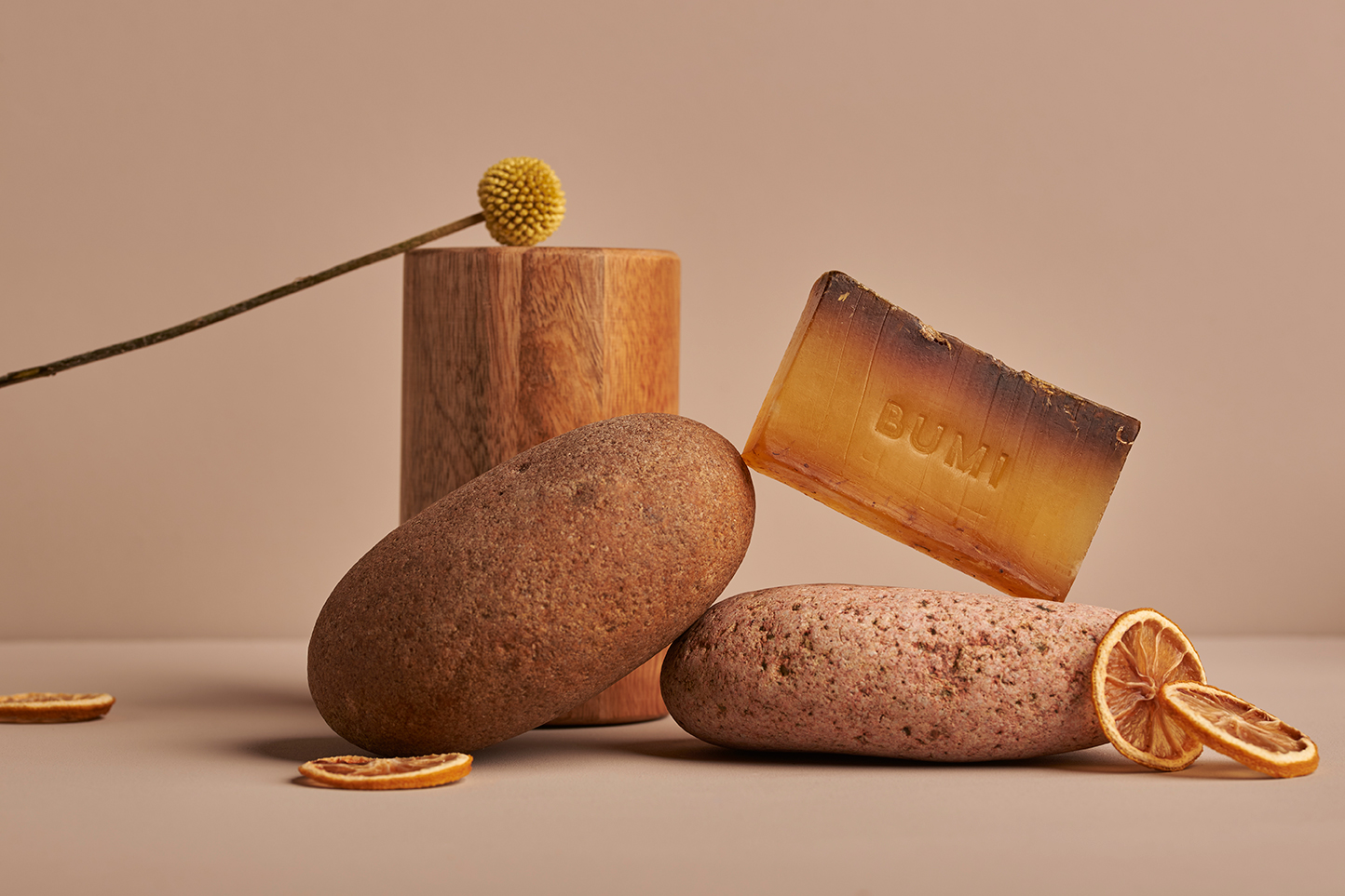 Soap Bar placed on rocks and wood with citrus around it.