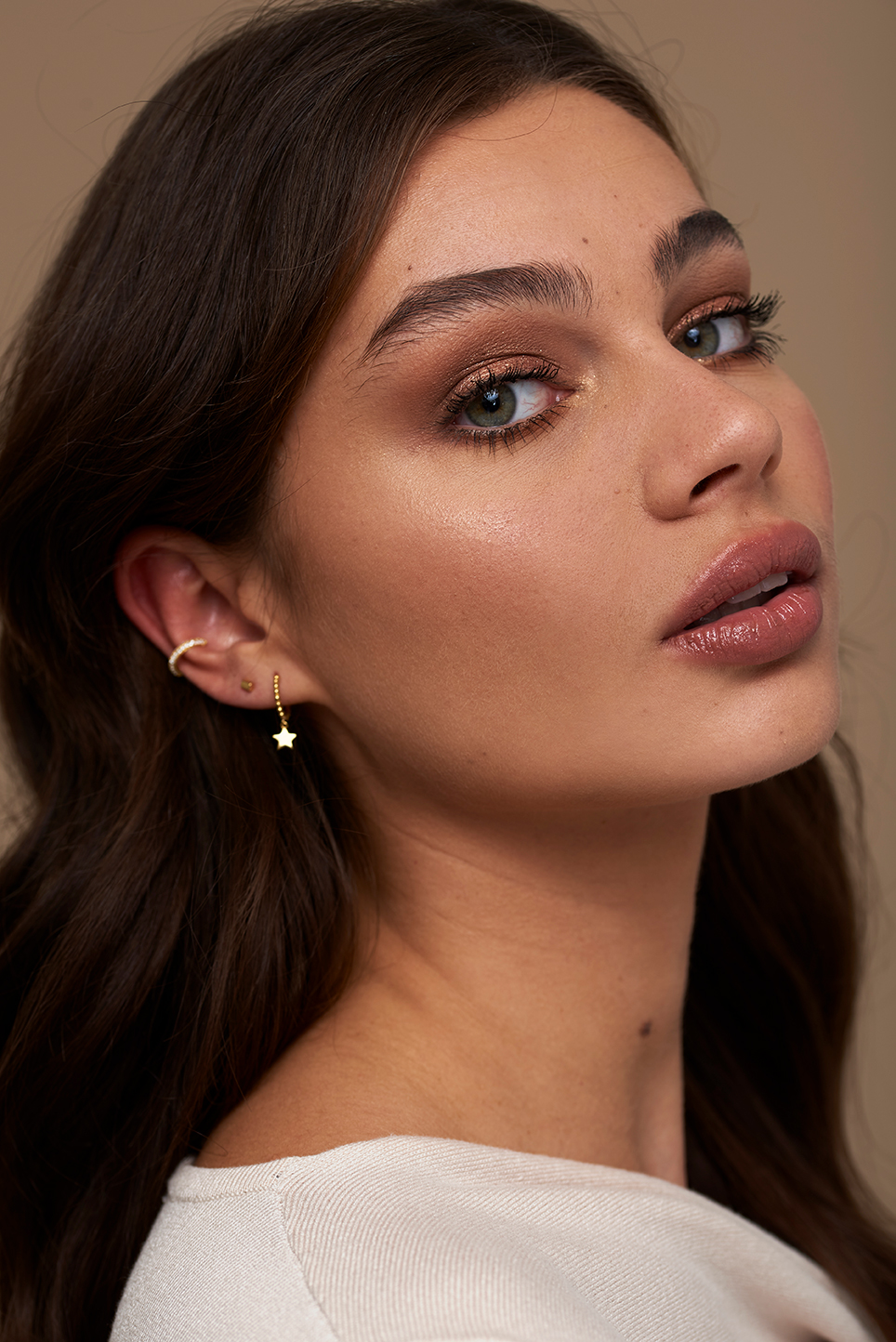 Model on a beige background showcasing three different earrings