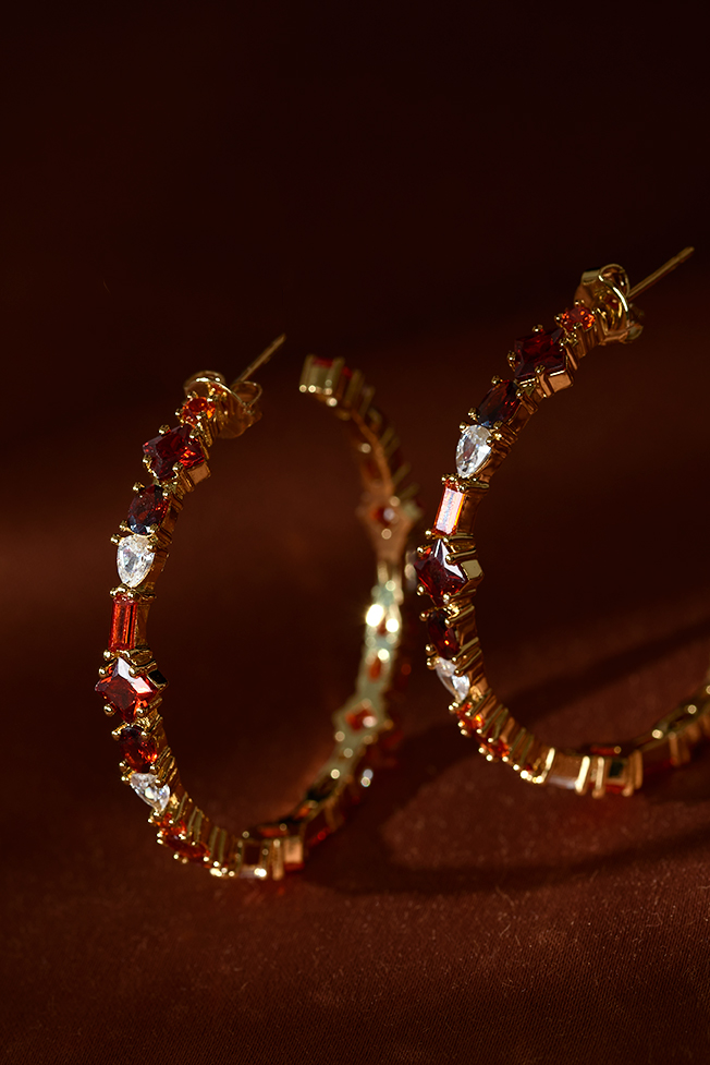 Two earrings placed creatively on a red background, lighted with a spot.