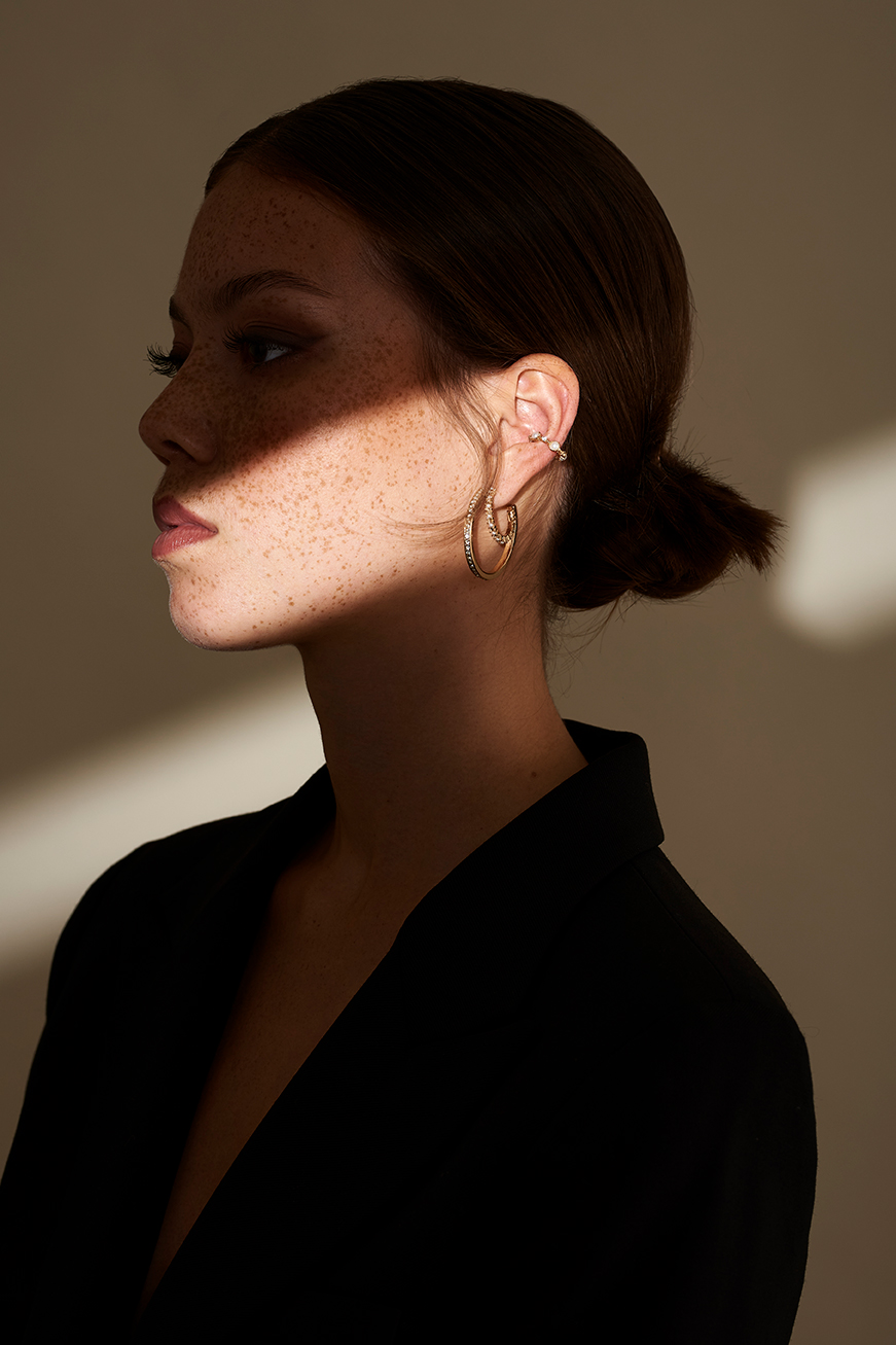 Model on a Taupe background with a light stripe on her jawline.